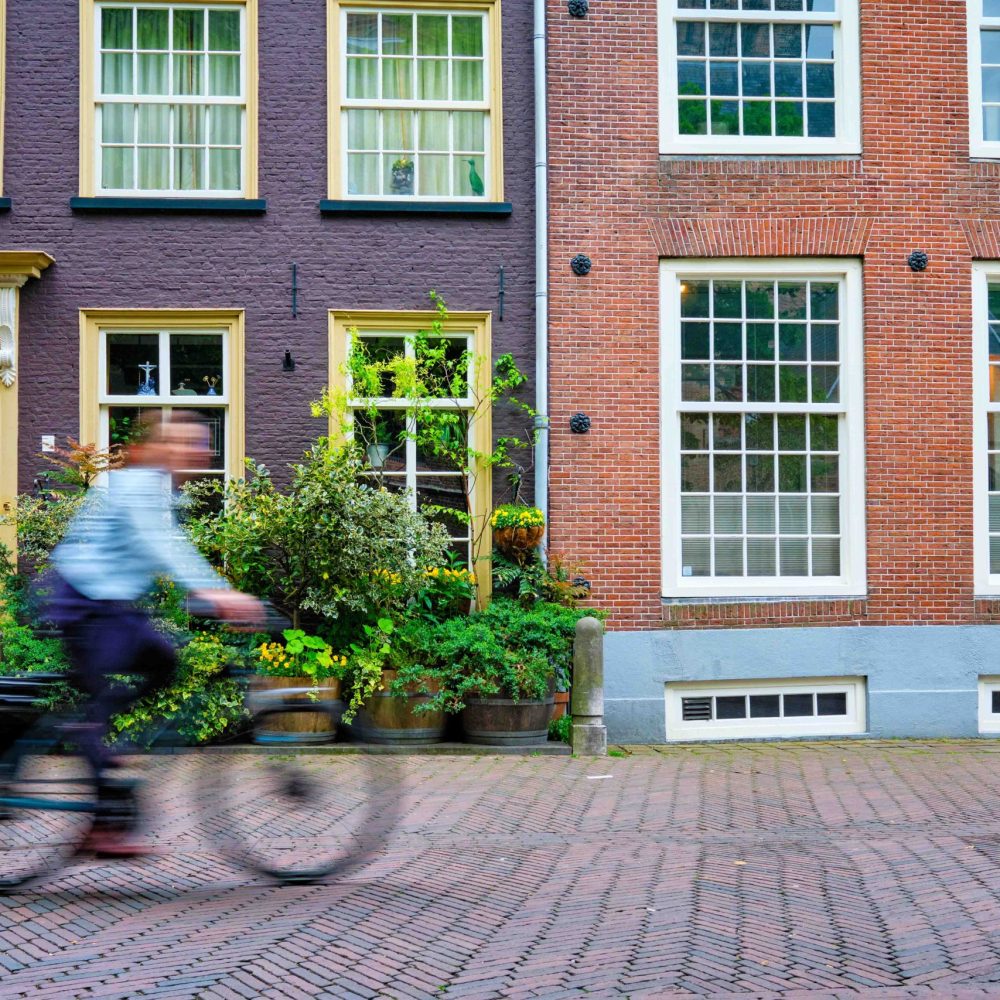 Bicycle rider cyclist man on bicycle very popular means of transoirt in Netherlands in street of Delft, Netherlands Motion blurred bicycle rider cyclist man on bicycle very popular means of transport in Netherlands in street with old houses of Delft, Netherlands